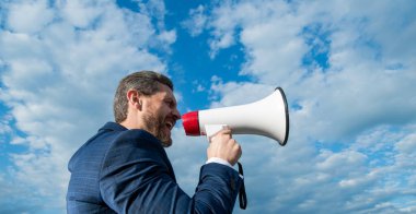 businessman shout in loud hailer on sky background.