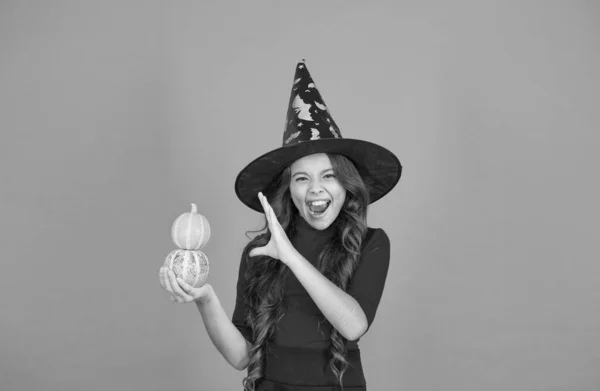 halloween shouting child in witch hat costume making spell with pumpkin, halloween magic.