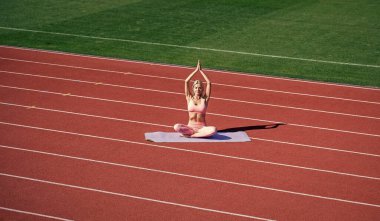 athletic female practice yoga on stadium. stretch sport workout. pilates trainer. yogi coach training. perfect body shape. mind and body balance. sexy fitness woman in sportswear. Work hard play hard.