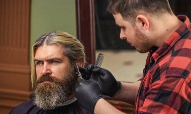 Kusursuz tarzına güveniyor. Yakışıklı, vahşi adam. Berber dükkanında kuaförlük. Erkek güzellik ve moda. Yeni bir saç stili yapıyorum. Atölyedeki erkek kuaför. Sakallı adam. saç ve sakal bakımı.