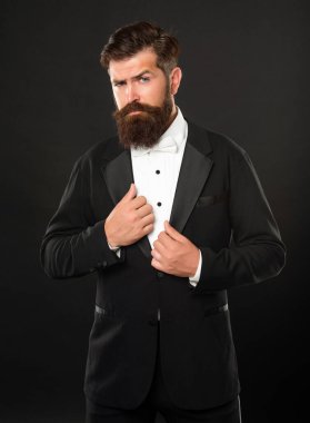 bearded man in tuxedo on black background, bow tie.