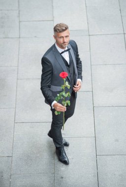 elegant man in tuxedo. man wearing bowtie suit outdoor. mature tuxedo man with red rose.