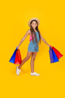 happy teen child with shopping bags on yellow background. black friday.