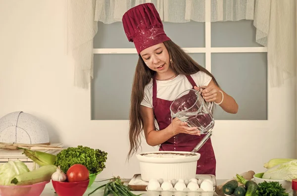 small girl baking in kitchen. kid chef cooking making dough. child prepare healthy food at home and wearing cook uniform. housekeeping and home helping. childhood development. Taste the delicious.