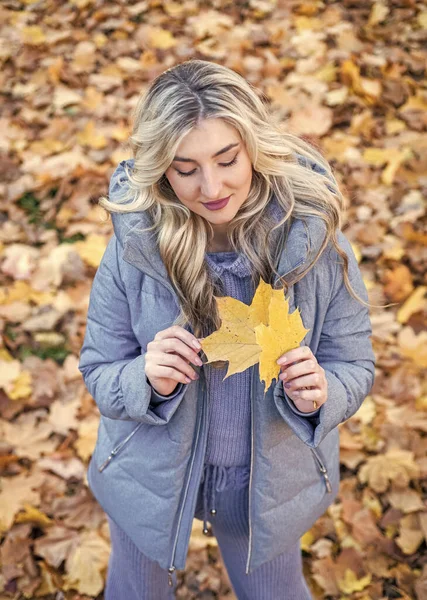 Time to relax. autumn fashion and beauty. pretty girl has long curly blond hair. lady in fall padded jacket in autumn forest. fallen leaves. nature beauty. beautiful blonde woman in puffer coat.