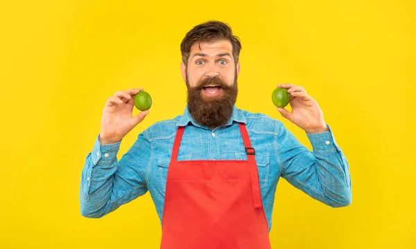 Surprised Man Red Apron Holding Fresh Limes Citrus Fruits Yellow — Stock Fotó