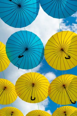 Blue and yellow umbrellas hanging bottom-up sky background.