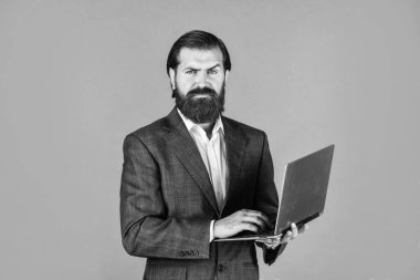 İletişim devrede. Modern iş dünyasındaki yeni teknoloji yalan söylüyor. Bilgisayarlı, beyaz sakallı hippi. Erkek çalışanın elinde finans raporu ve laptopta ortak çalışma alanı araştırmaları var..