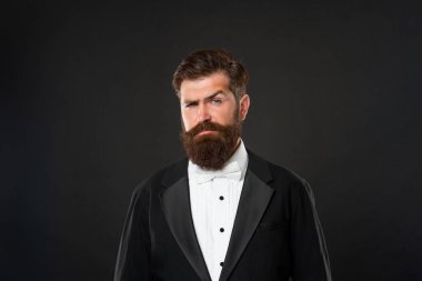 brutal gentleman in tuxedo on black background, fashionist.