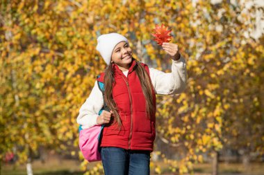 cheerful teen girl at school time outdoor in autumn season with backpack.