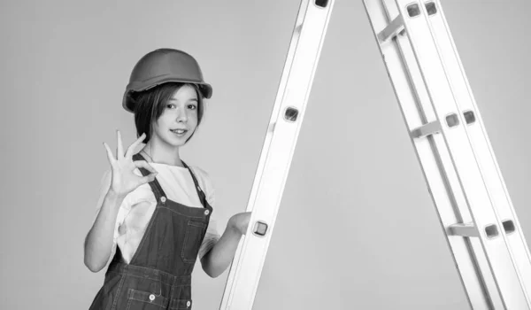 girl in helmet plays builder. building and renovating. kid build construction. engineer teen is construction worker. international workers day. electrician on stepladder.