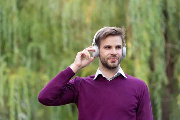 young handsome guy listen music in headphones outdoor.