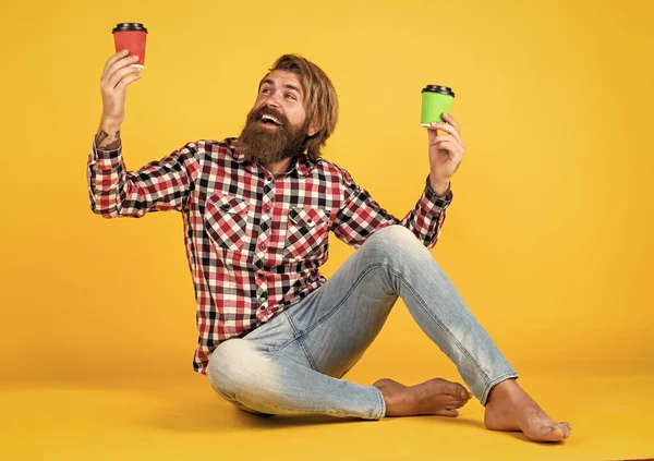 Kareli gömlekli, modaya uygun saç stili olan beyaz, olgun bir hippi sabah kahvesini kağıt bardaktan, sabah enerjisinden seçer..