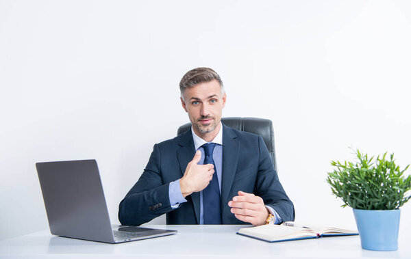 mature businessman sitting and presenting himself in business office.
