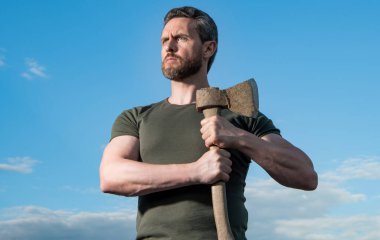 caucasian man with axe. caucasian man hold ax. brutal man on sky background.