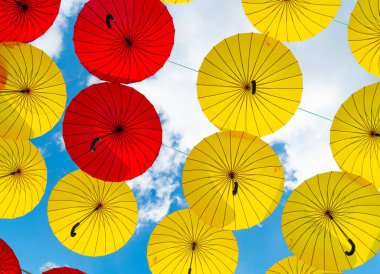 Bright color umbrellas hanging bottom-up sky background.