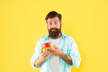 confused bearded guy hold morning coffee on yellow background, morning.