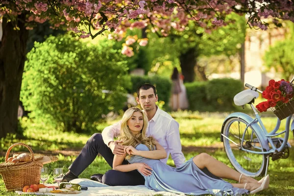 First meet. summer holiday trip. girl and man under sakura. couple in love drinking wine during romantic dinner in park. picnic of couple in love at vintage bike. family relationship and friendship.