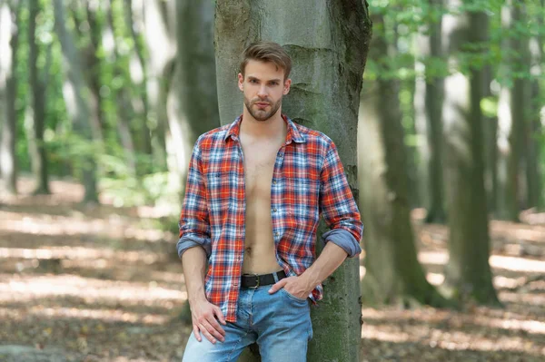 Handsome Unshaven Man Unbuttoned Lumberjack Shirt Standing Tree Forest Background — Stockfoto