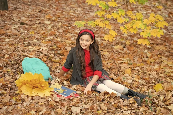 笑顔ティーン女の子で学校の制服ホールド秋カエデの葉でバックパックとワークブック屋外 — ストック写真