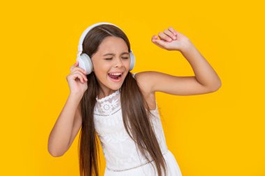 singing teen kid listen music in headphones on yellow background.