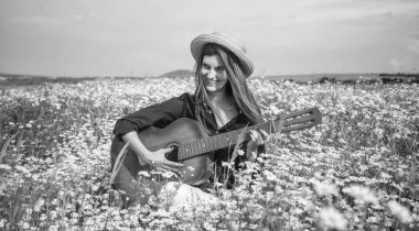 Hafta sonunun tadını çıkarıyorum. Tatil. Özgürlük duygusu. Güzel bir kadın papatya çiçeği tarlasında gitar çalıyor. Yaz ya da bahar doğası. Mevsimsel güzellik. Şapkalı genç kız Meadow 'da country müzik çalıyor..