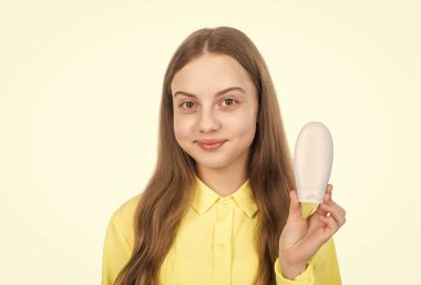 tebessüm eden çocuk şampuan ya da saç kremi şişesi sunuyor beyaz, saç bakımına izole edilmiş..