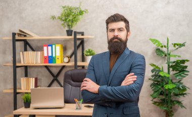 mature entrepreneur in jacket standing crossed hands at office with copy space, charisma.