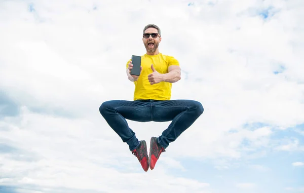 Man Jumping Presenting Smartphone Sky Background Thumb — Stockfoto