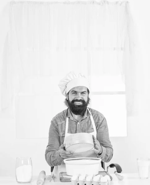I love my job. mature bearded man wear chef hat using sieve. male cook preparing food in home kitchen. brutal hipster in apron cooking meal. time for eating. happy baking. concept of housekeeping.