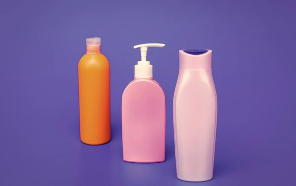 Toiletry and cosmetic plastic containers for liquid shower and bath products packing in row blue background copy space, bottles.