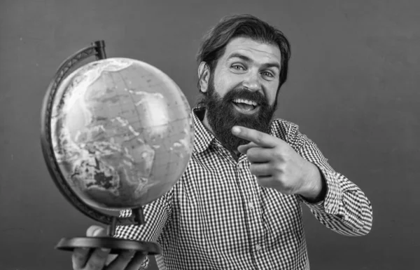 look over there. back to school. informal education. happy mature teacher pointing at globe. bearded man geographer work in classroom with map. prepare for exam. college lecturer on geography lesson.