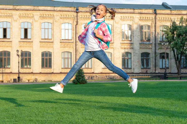 Happy teen girl jumping in school yard outdoors, back-to-school.