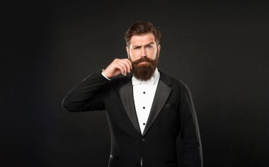 serious man in tuxedo bow tie with moustache. man in formalwear on black background. male formal fashion.