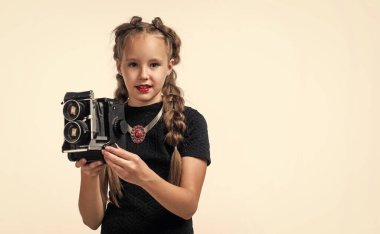 Mükemmel bir çocuk fotoğrafı. Mutlu çocukluk. Güzellik ve moda. Klasik kameralı neşeli çocuk beyaza izole edilmiş. Saçları örgülü, fotoğraf çeken retro genç kız. fotoğraflama.