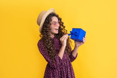 surprised kid with curly hair hold present box on yellow background.