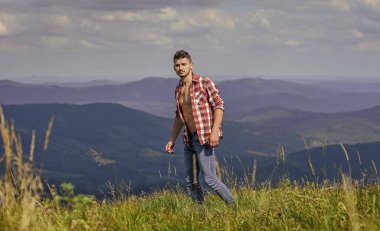 Doğanın gücü. Düğmeleri iliklenmemiş adam dağ manzarasının en üstünde duruyor. Güçlü yürüyüşçü kaslı gövdesi. Atletik kaslı adam dağları gevşetiyor. Yürüyüş konsepti. Kaslı turist dağ yamacında yürüyor.