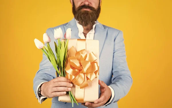 well groomed man in wedding formalwear has beard hold tulip flower and present box, valentines day.