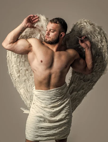 athletic guy with strong muscles in cupid angel wings, valentines day.