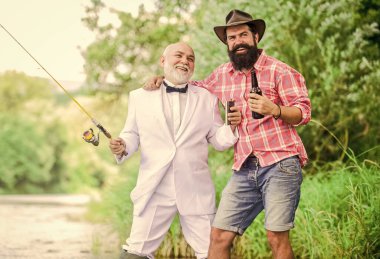 Erkekler doğayı rahatlatıyor. Eğlen ve rahatla. Hafta sonu tatili. Balık tutma becerileri. Oltayı oltaya getirin. Balık tutmak ve bira içmek. Sakallı adam ve zarif iş adamı birlikte balık tutuyor..