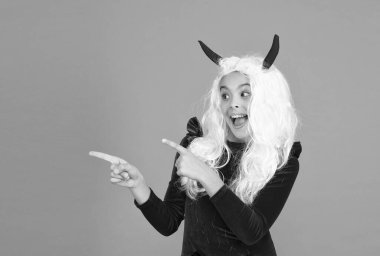 Beyaz saçlı, işaret eden bir çocuk. Ürkütücü ve ürkütücü. Karnaval kostüm partisi. Şeker mi şaka mı? Bayramları kutlarız. çocukluk. Mutlu cadılar bayramı şeytan kızı. Boynuzlu ergen çocuk.