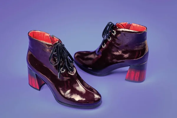 female leather stylish footwear. pair of fashionable leather shoes with red heel. high heel burgundy boots. ankle boots on blue background. shoe store. shopping concept.