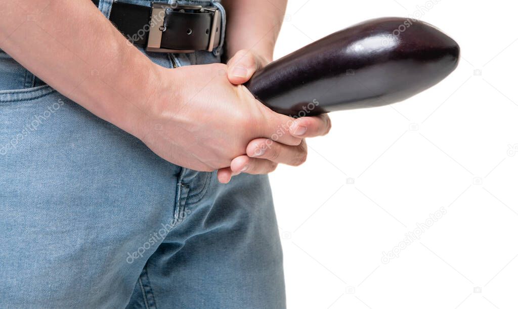 Man crop view holding eggplant at crotch level imitating penis enlargement isolated on white, copy space.