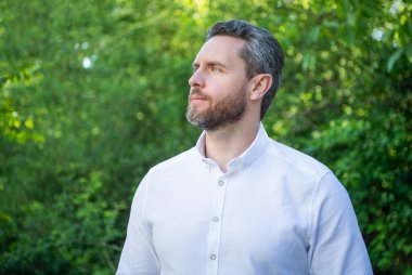 Handsome businessman man looking aside natural background.