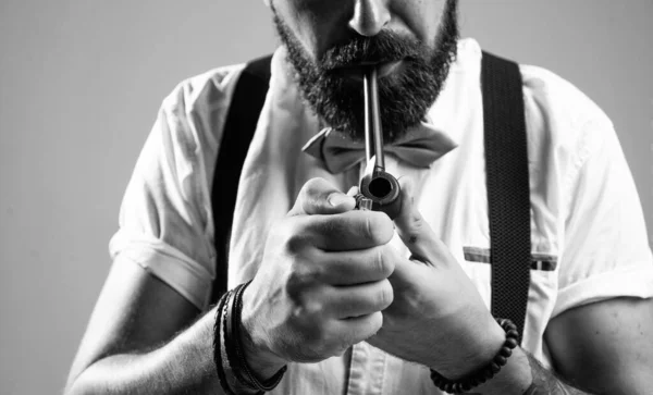 brutal bearded male with stylish look smoking pipe, smoker.