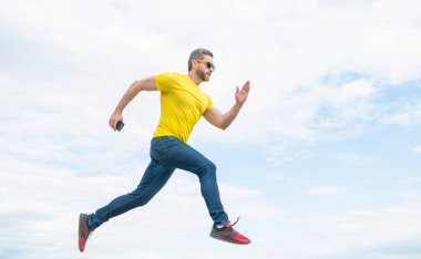 man running with smartphone on sky background.