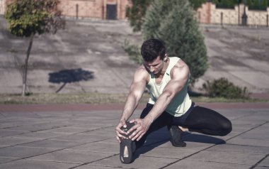 Maço eşofman kentsel peyzaj üzerinde uygun. Güneşli yaz gün açık havada üzerinde eğitim atlet. Kasları egzersiz önce ısınma ve germe adam. Spor ve fitness. Sağlıklı yaşam konsepti.