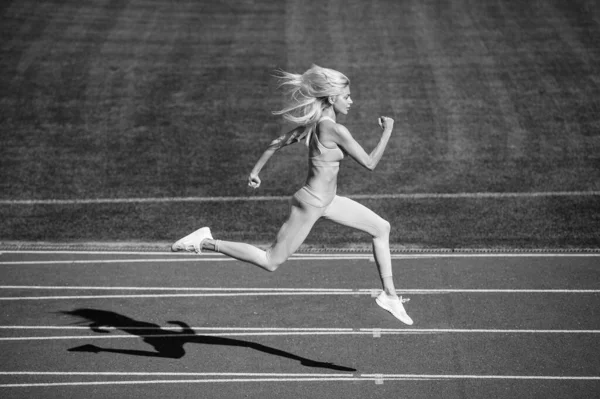 fit lady in fitness wear running on stadium racetrack while sport workout, energy.