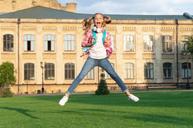 Happy active teenage girl jumping in school yard outdoors, September 1.