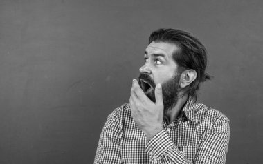 Kafkas hippiler yeşil arka planda şaşkınlık hissederler. kopyalama alanı. Tahtanın arka planında olgun bir öğretmene sürpriz oldu. Vahşi sakallı adam sıradan bir kareli gömlek giyer. insan duygularını ifade etmek.